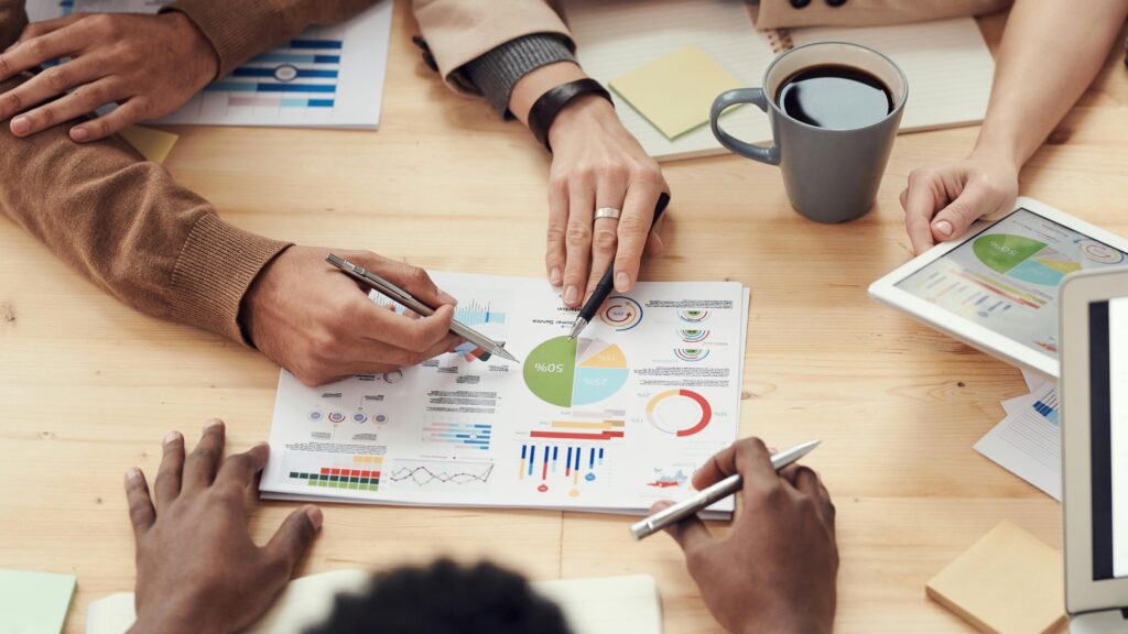 Bird's eye view of people around a table looking at charts