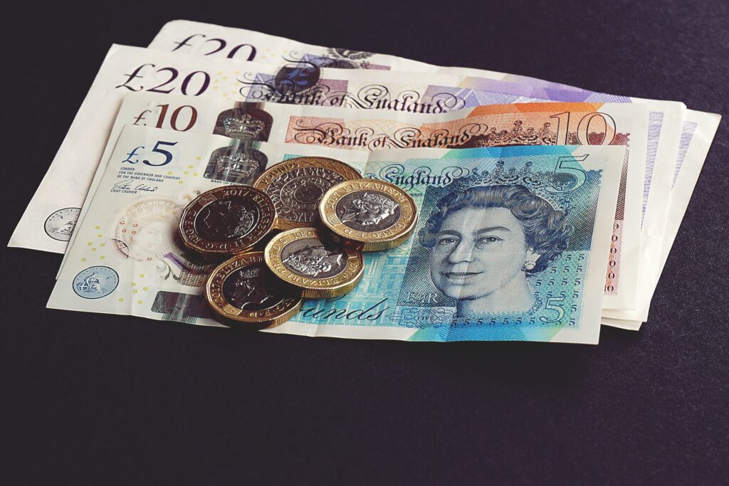 Pile of bank notes and coins on black background