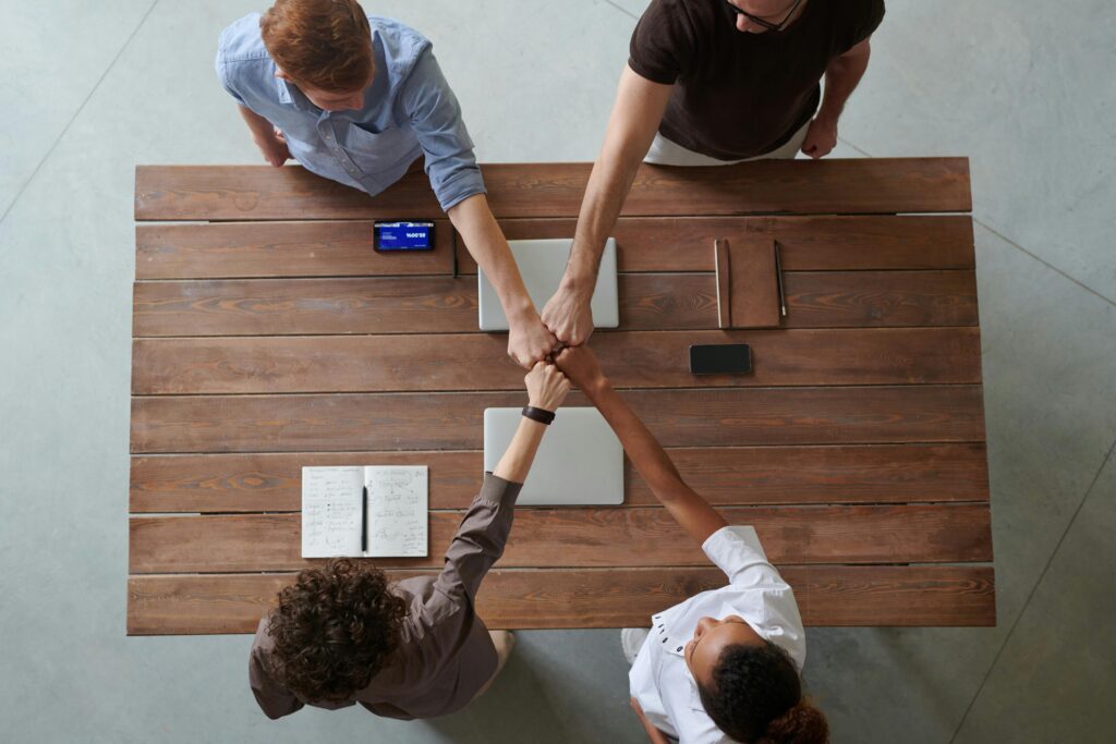 Bird's eye view of four people standing around a table fist bumping